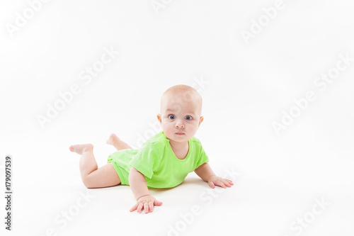 Cute curious baby lies on her stomach and looking at the camera