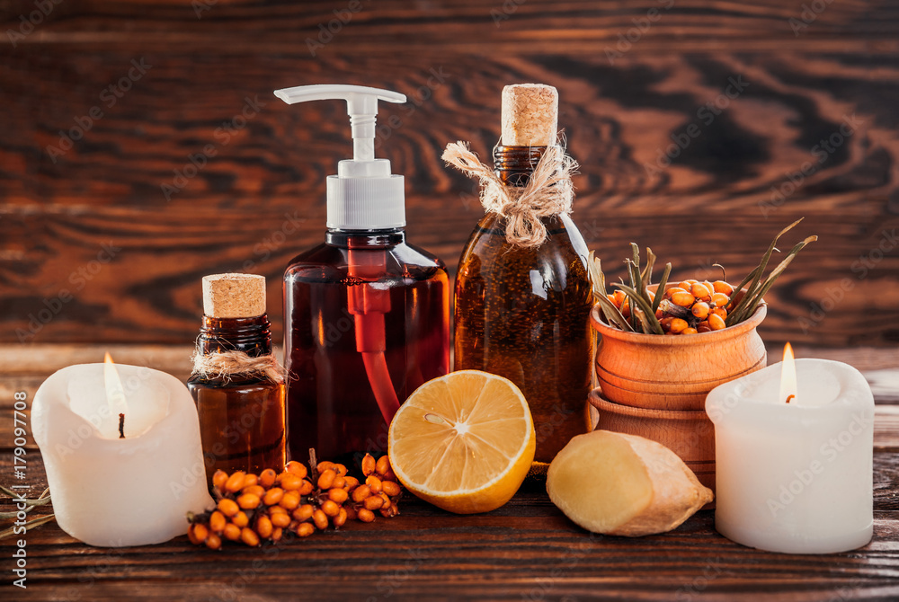 Spa essentials including sea buckthorn, lemon and ginger oils and candles. Organic cosmetics concept Spa essentials including sea buckthorn, lemon and ginger oils and candles. Organic cosmetics concept