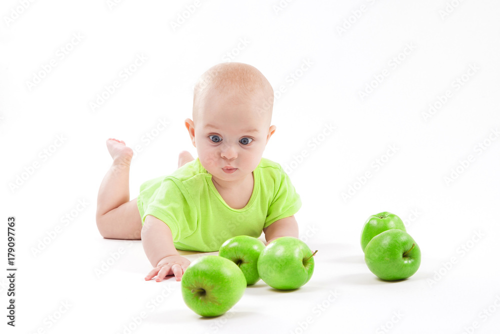 cute surprised baby looks at green apple on a white background cute surprised baby looks at green apple on a white background