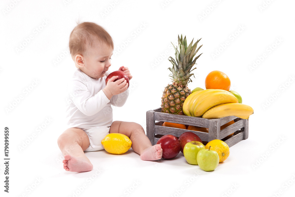 looking at fruit cute smiling baby on white background among fruits. Photo with depth of field looking at fruit cute smiling baby on white background among fruits. Photo with depth of field