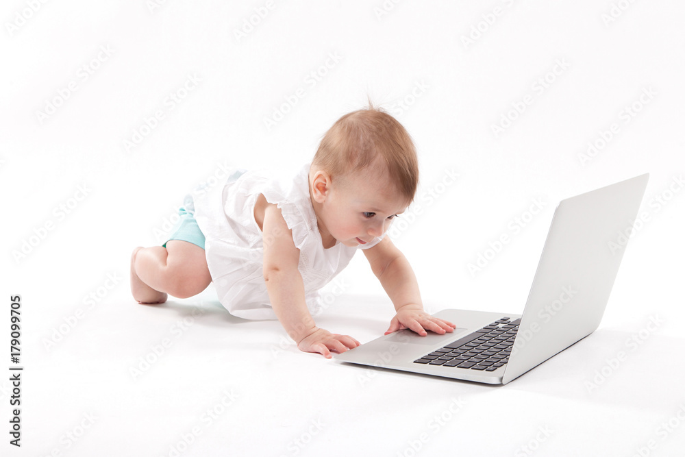 curious smiling child sitting near the laptop on a white background curious smiling child sitting near the laptop on a white background