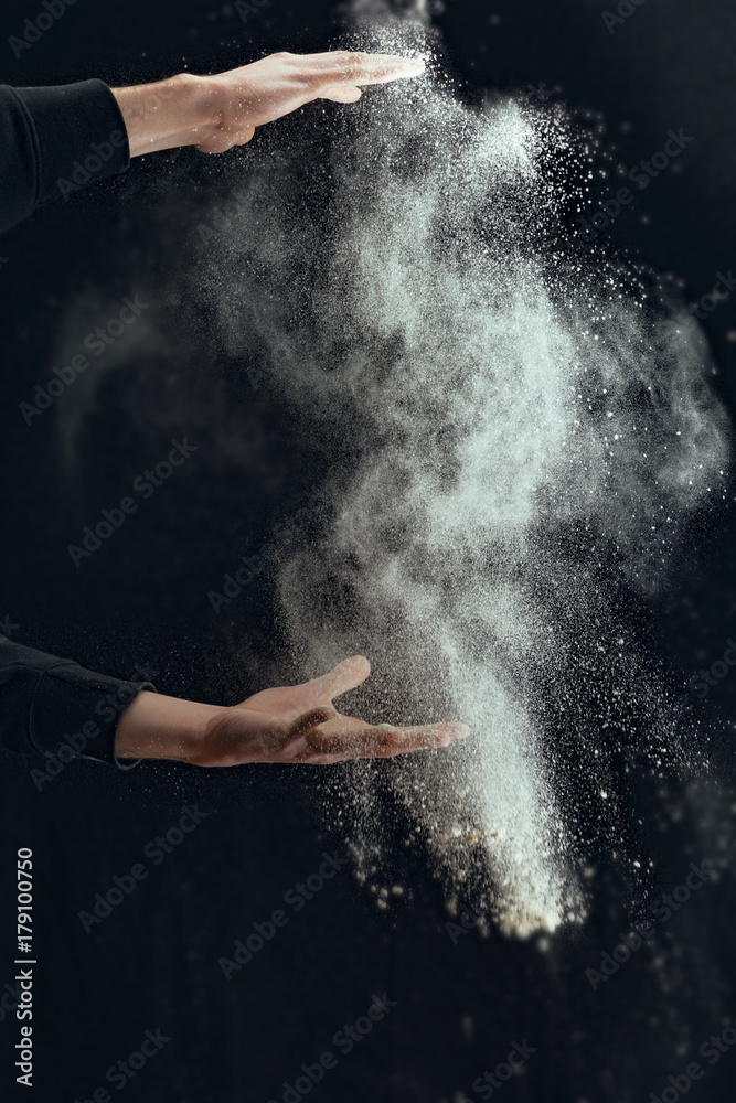 Man hands throw white powder on dark background