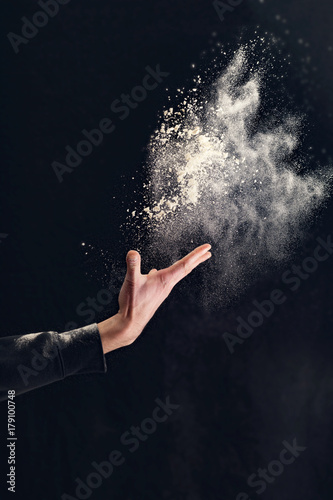 Man hands throw white powder on dark background