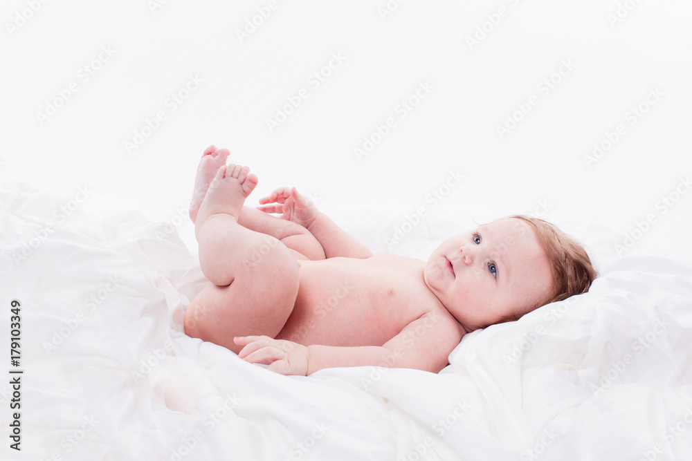 naked baby on a white background lying on his back and smiling naked baby on a white background lying on his back and smiling