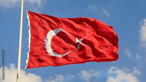 Slow Motion, Zoom Out. Turkish Flag waving in the wind over blue sky with white clouds. The flag of Turkey; A red flag featuring a white star and crescent often called as moon-star (Ayyildiz) photo
