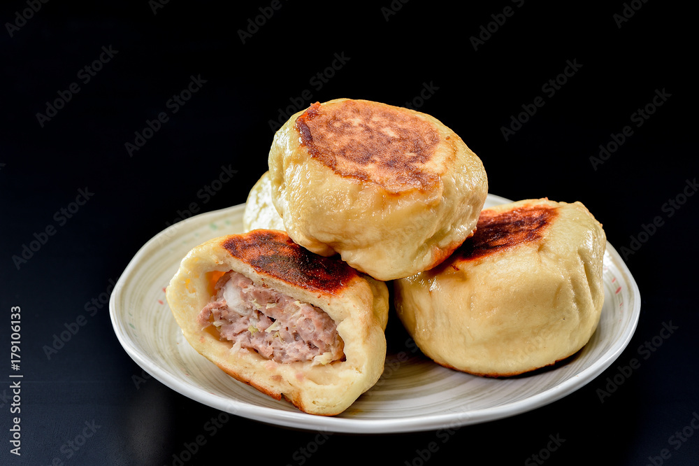 chinese traditional food pan-fried bun in white plate isolated on black background