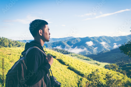 Carefree happy man enjoying nature on top of mountain cliff with sunrise. Freedom concept. Sunbeams. Enjoyment.