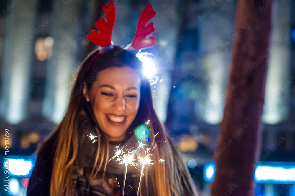 Close up of woman holding sparkler on the street. Young woman celebrating an event the New Year is coming