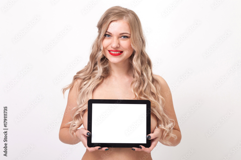 naked to the waist beautiful blonde with big breasts standing on a white background and holds a a tablet tablet and smiling at the camera, selective focus on the tablet naked to the waist beautiful blonde with big breasts standing on a white background and holds a a tablet tablet and smiling at the camera, selective focus on the tablet