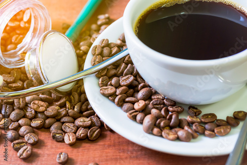 Cup of dark coffee  with coffee beans and stethoscope on  wooden background. Health  concept of who like drink a coffee.