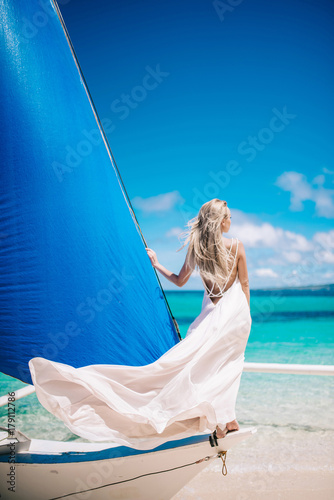 beautiful bride on wedding day ready for travel by sail boat.