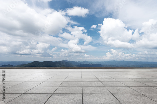 empty marble floor with green hill in cloud sky © zhu difeng