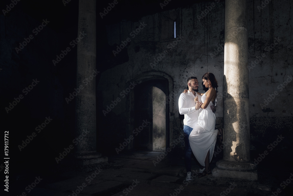 Hombre y mujer enamorados en un templo antiguo iluminados por la luz del sol al atardecer