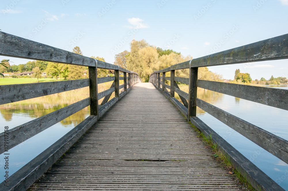 boardwalk with handrails over calm lake with trees