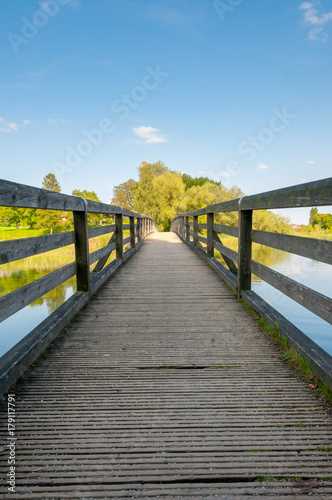 Fototapeta Naklejka Na Ścianę i Meble -  boardwalk with handrails over calm lake with trees