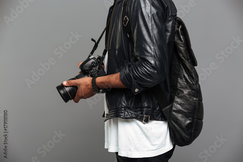 Cropped photo of stylish african man with backpack holding photo camera