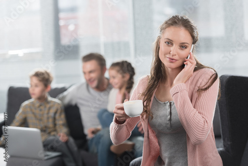 woman with coffee talking on phone at home