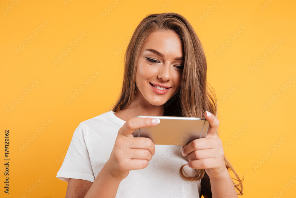 Happy cute beautiful young woman play games by mobile phone Happy cute beautiful young woman play games by mobile phone