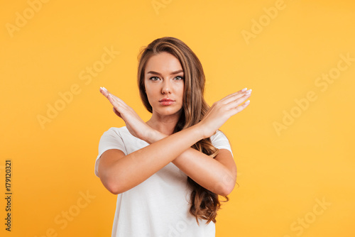 Serious caucasian woman standing near copyspace showing stop gesture.