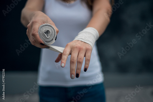 girl dressed in white t-shirt preparing for the competition waving her hands with a bandage