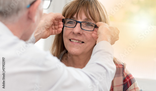 Fototapeta Naklejka Na Ścianę i Meble -  Mature woman testing new eyeglasses, light effect