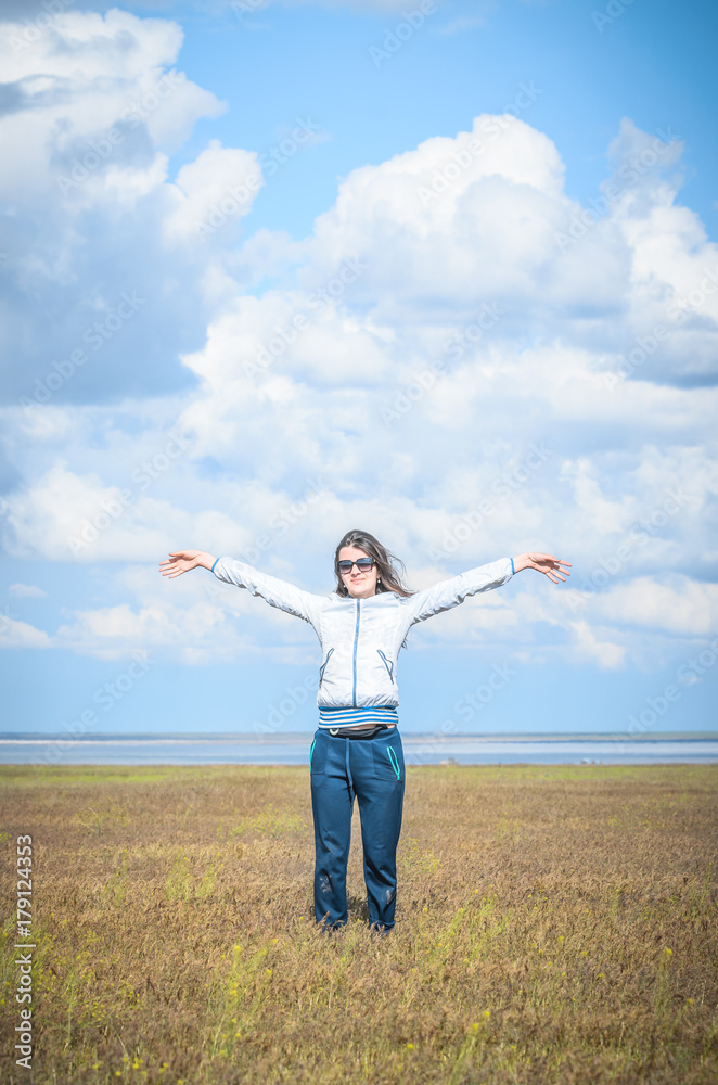Young woman smiling in the midst of a orange lawn, she looks at the camera, so carefree. Steppe landscape. Baskunchak lake at background. Travel picture Young woman smiling in the midst of a orange lawn, she looks at the camera, so carefree. Steppe landscape. Baskunchak lake at background. Travel picture