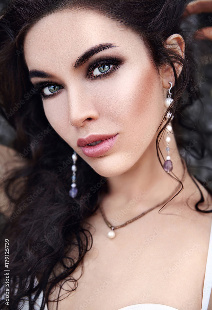 portrait of beautiful caucasian woman model with evening makeup and dark long hair posing outdoors portrait of beautiful caucasian woman model with evening makeup and dark long hair posing outdoors