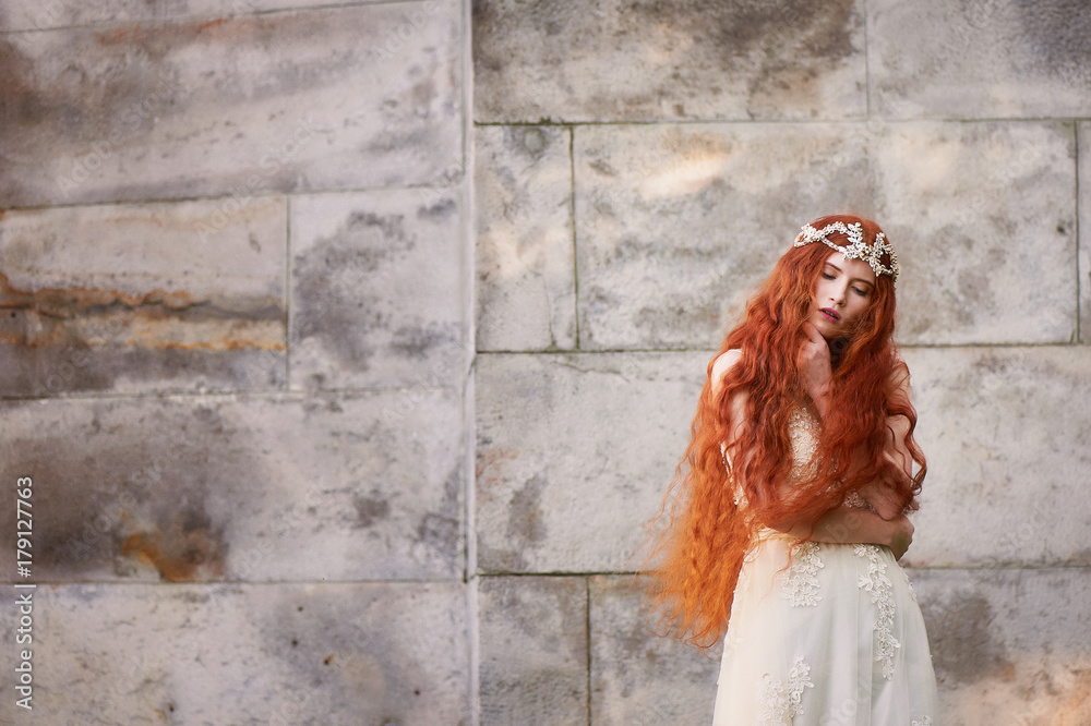Φωτογραφία Beautiful red-haired girl with long curly hair in the bride, in a long lace dress