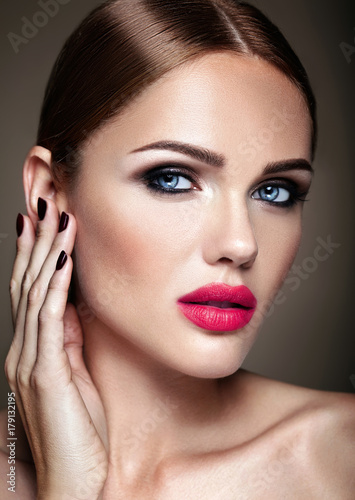 Portrait of beautiful girl model with evening makeup and romantic hairstyle touching her skin. Pink lips
