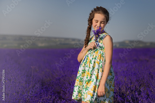 girl standing in a field of lavender and sniffing flowers