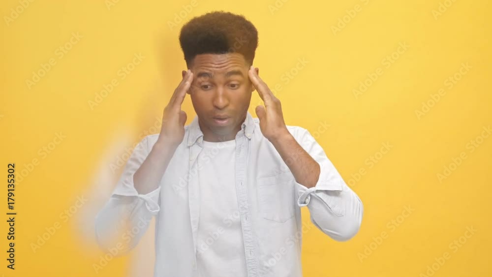 Young african man in shirt having throbbing headache and touching his temples over yellow background Young african man in shirt having throbbing headache and touching his temples over yellow background