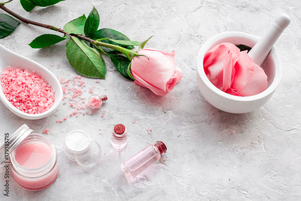 Make cosmetics with rose oil. Mortar with rose petals and pestle on grey background Make cosmetics with rose oil. Mortar with rose petals and pestle on grey background