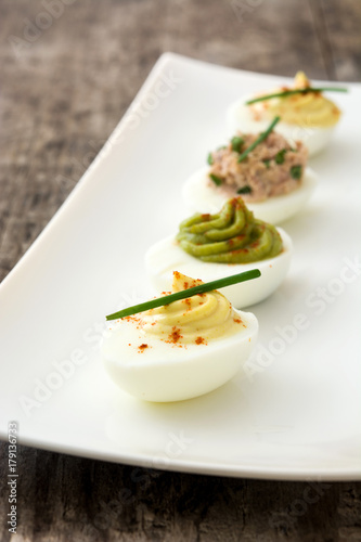 Variety of stuffed eggs with avocado and tuna  on wooden table