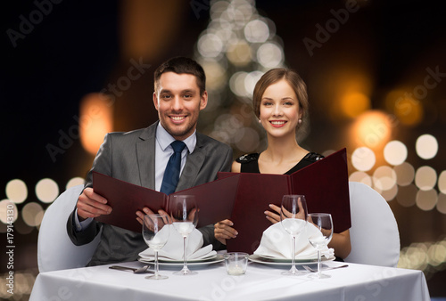 smiling couple with menus at christmas restaurant