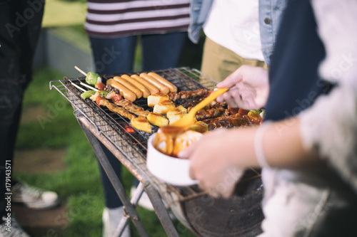 Asian group of Friends making barbecue and grilled shashliks on grate party in outdoor garden photo