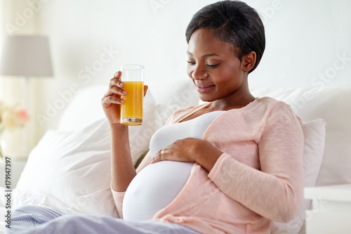 pregnant woman drinking orange juice in bed