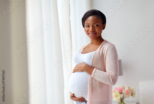 pregnant african american woman at home window