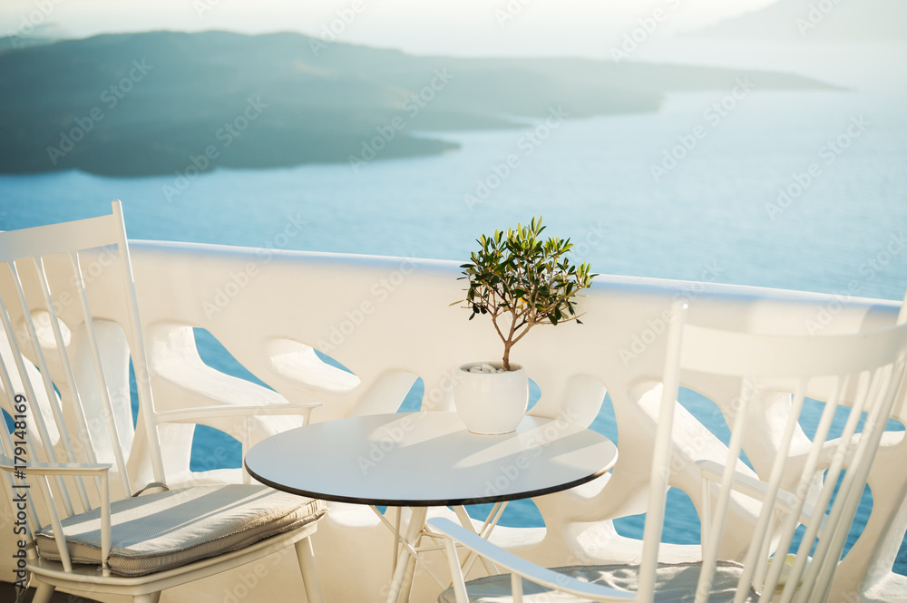 Two chairs and table on the terrace with sea view. Santorini island, Greece.