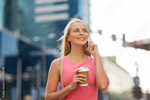 woman with coffee calling on smartphone in city