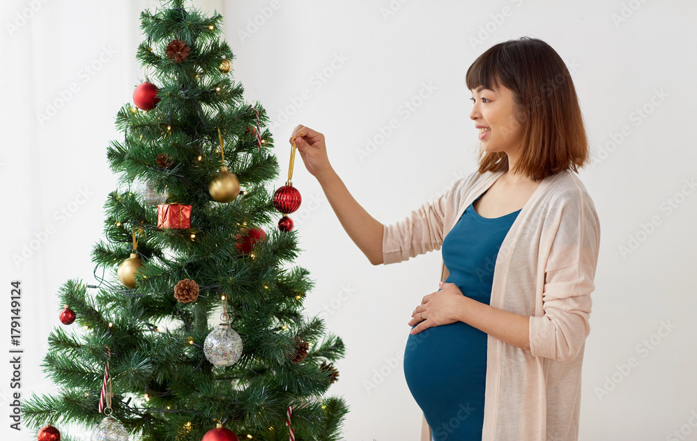 pregnant woman decorating christmas tree at home pregnant woman decorating christmas tree at home