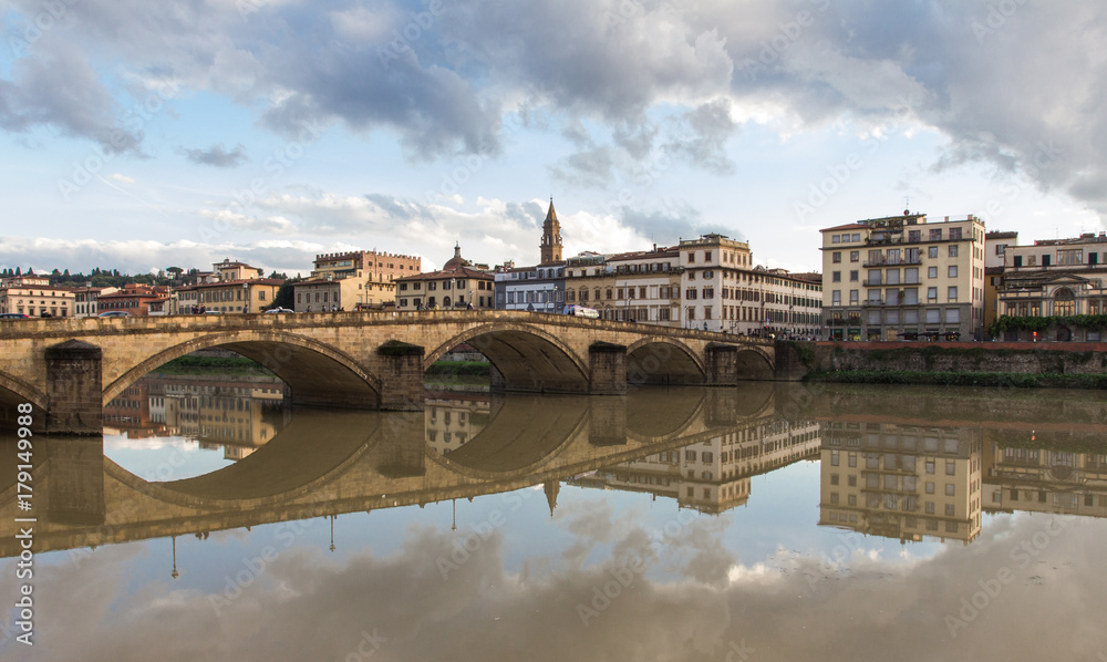 The embankment of Arno river. The bridge across the river, Florence, Italy. Reflection in the water.