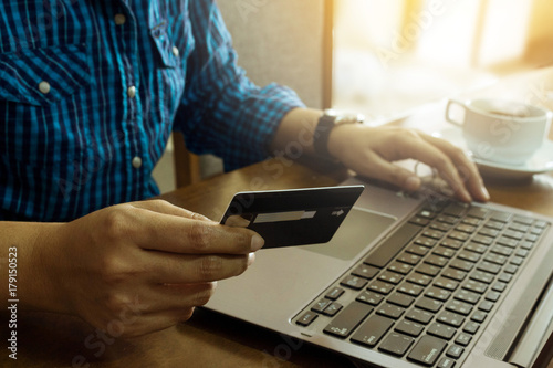 Online shopping and payment by credit card. Hand holding credit card and using laptop on table. E commerce concept. Selective focus.