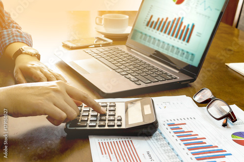 Business financial man using calculator and laptop analysis accounting on office desk. Glowing business concept. Selective Focus.