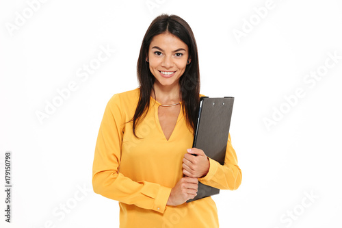 Close-up portrait of happy successful businesswoman in yellow shirt holding folder with documents, looking at camera