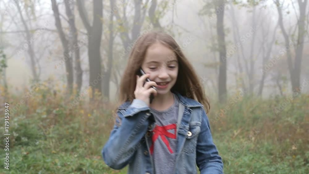 Happy beautiful girl walking by forest and talking cell phone. Portrait steady cam shot. Camera flies around girl. Happy beautiful girl walking by forest and talking cell phone. Portrait steady cam shot. Camera flies around girl.