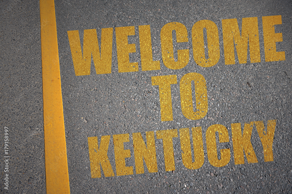 asphalt road with text welcome to kentucky near yellow line.