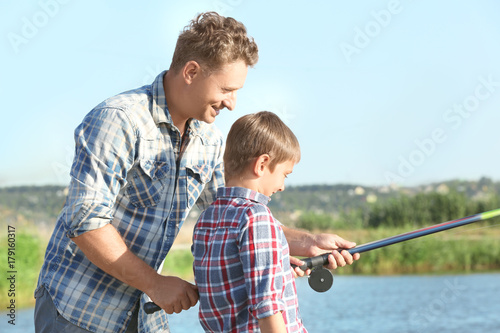 Father with son fishing on pond together