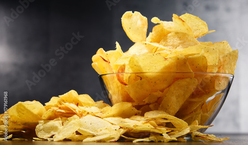 Composition with bowl of potato chips on wooden table photo