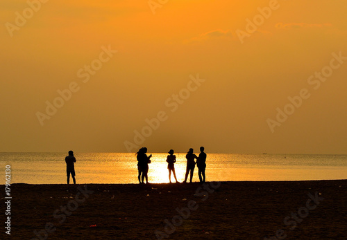 Silhouette of people on beach has sunset background