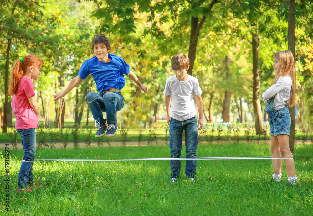 Cute little children jumping rope in park